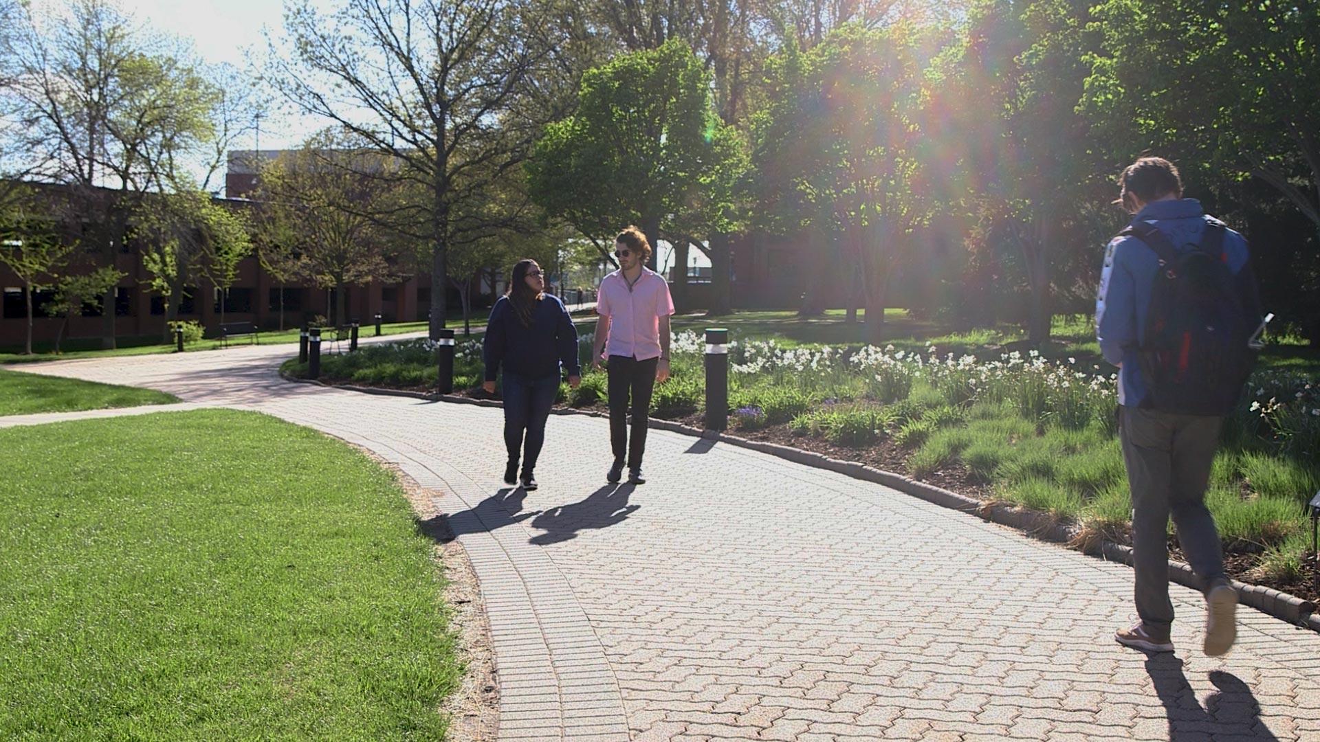 Students walking the path between Galileo's Pavilion and the COM building